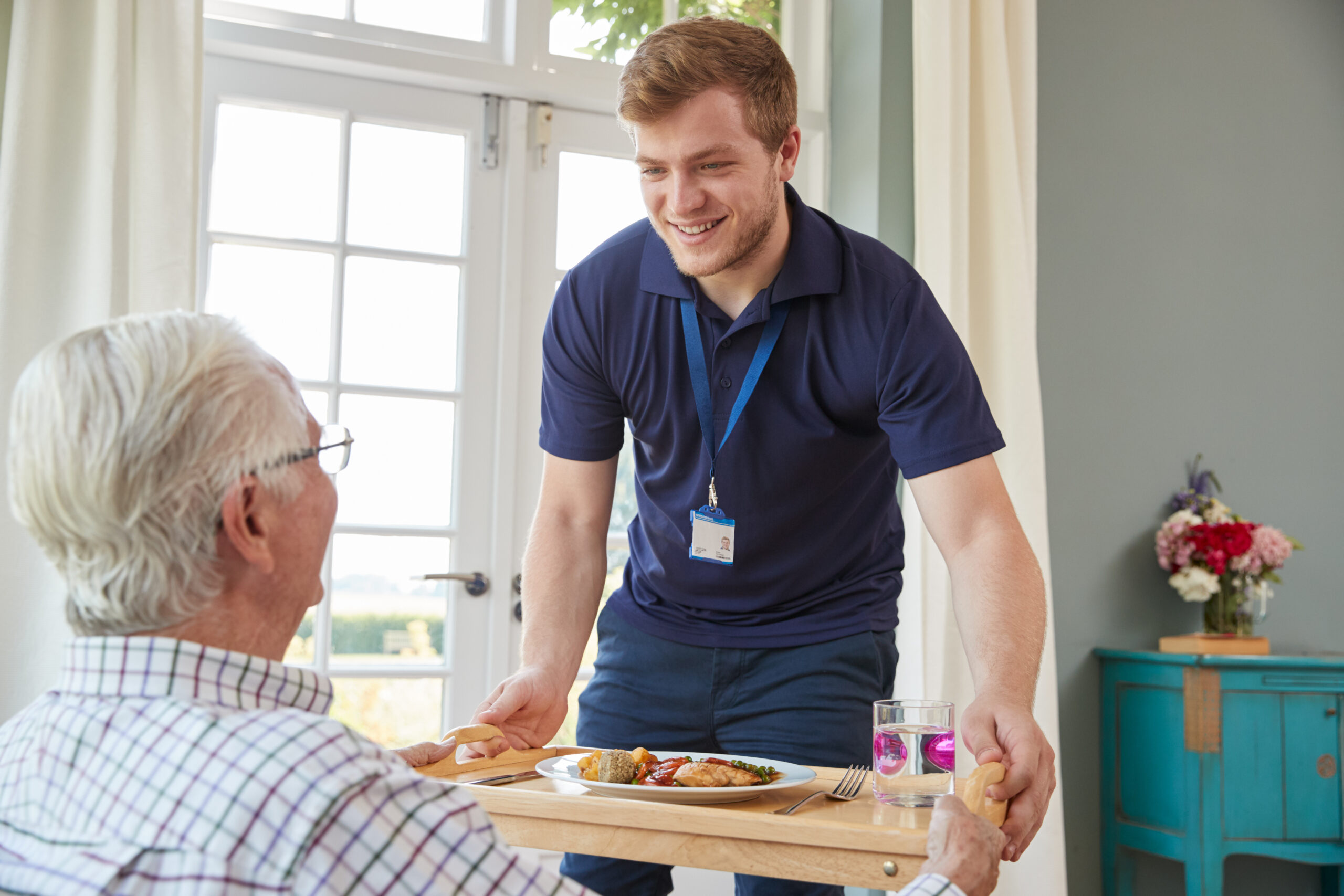 A healthcare worker brings a meal to an elderly client